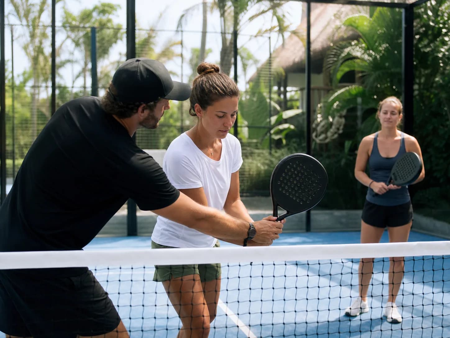 Coach helping a beginner with grip and stance on a padel court